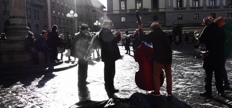 Musicisti in controluce sotto la colonna dell’Abbondanza in piazza della Repubblica.